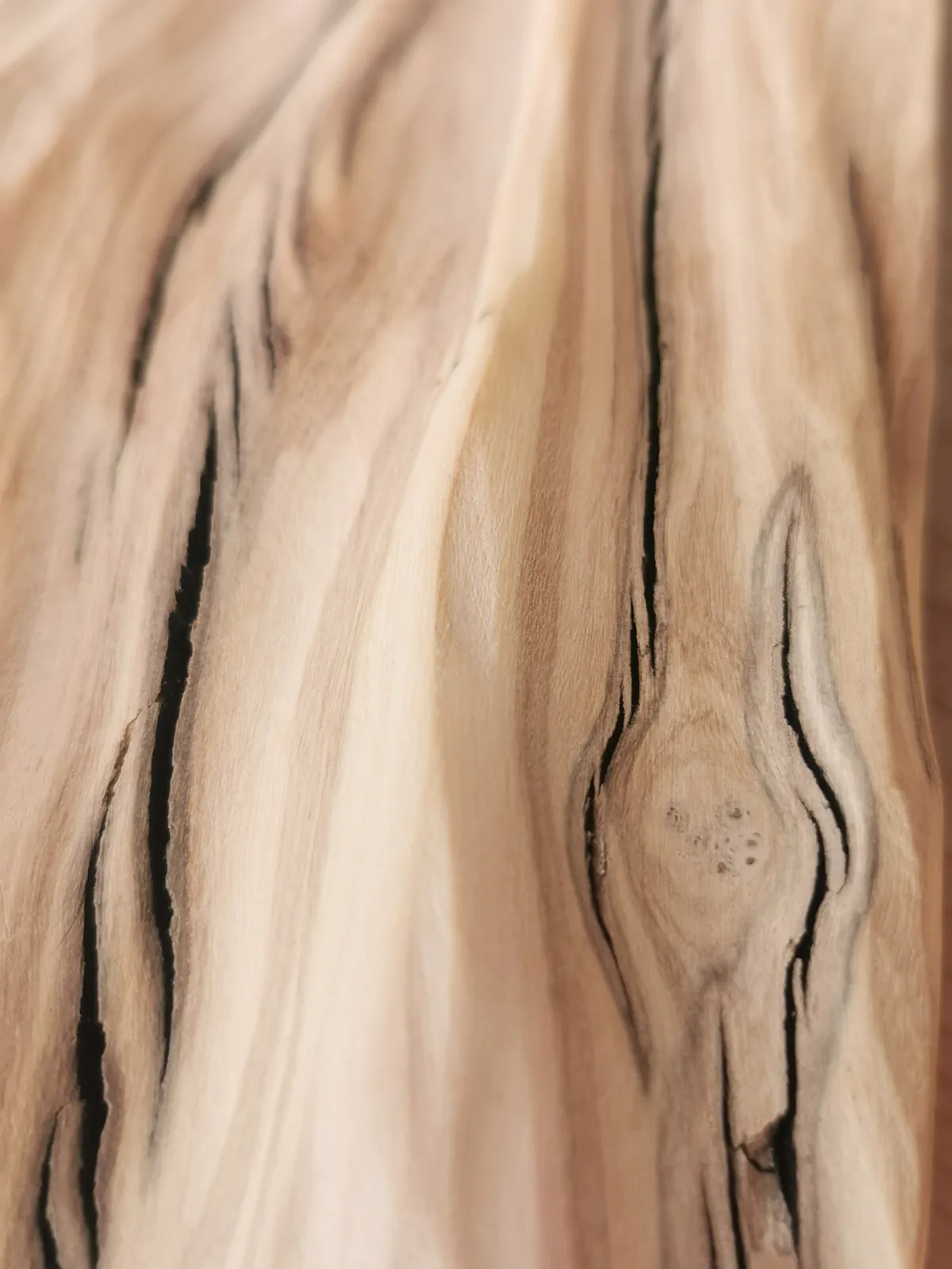 Macro di legno chiaro levigato percorso da venature e da una fessura profonda